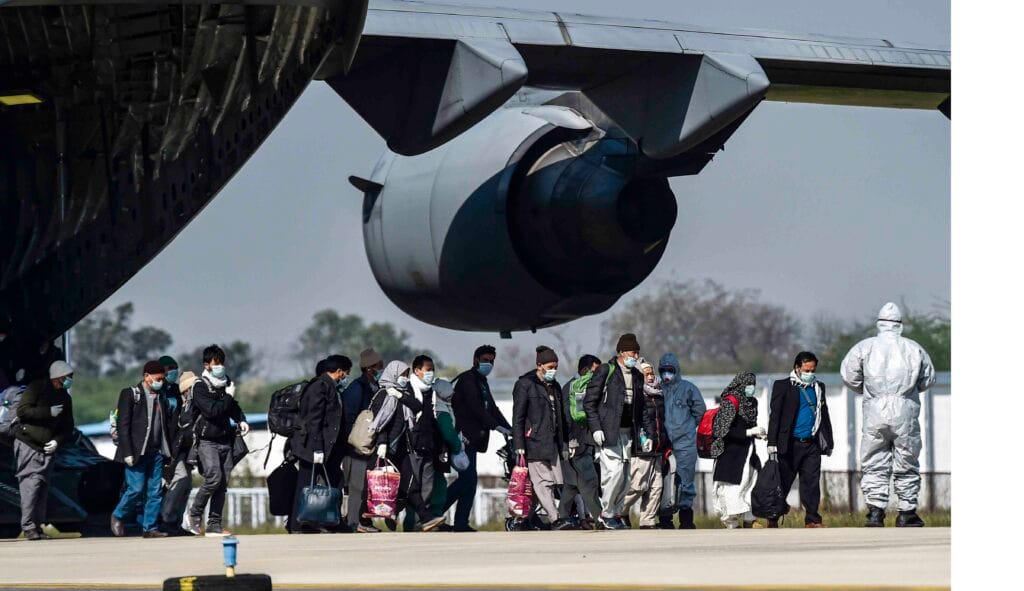 Indians deported globally in 2025 waiting at international airport terminal with luggage