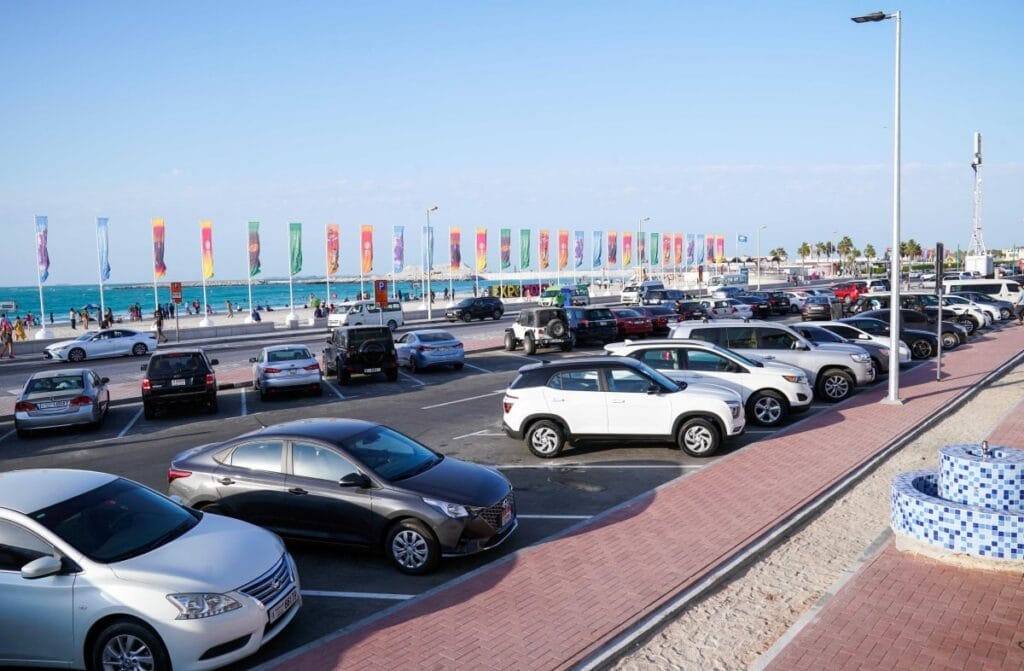 Sunny open parking area in a Dubai residential community filled with sedans and SUVs.