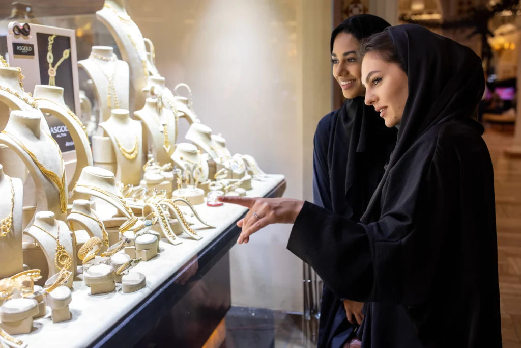 Woman checking on 22K gold necklace in Dubai jewelry store during price correction.