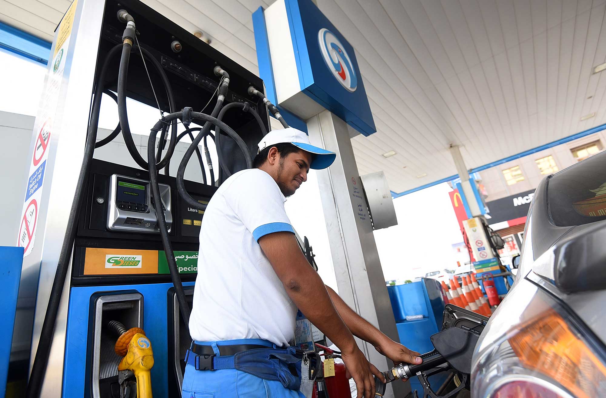 UAE fuel station worker filling up cars at a station reacting to the UAE fuel price forecast 2026.