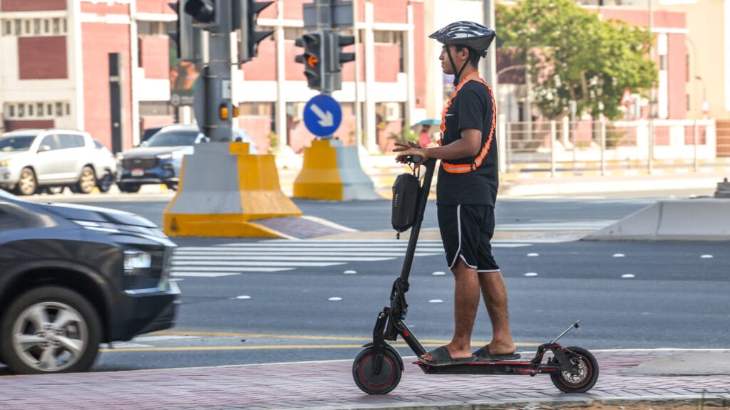 Rider wearing a helmet and vest on a designated Dubai e-scooter track near Downtown