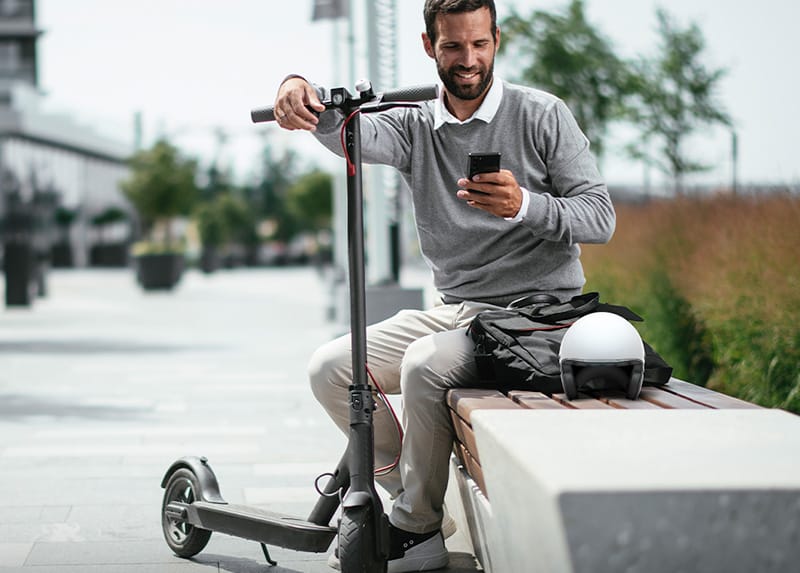 Rider using the Dubai e-scooter permit guide app on a smartphone near JLT.